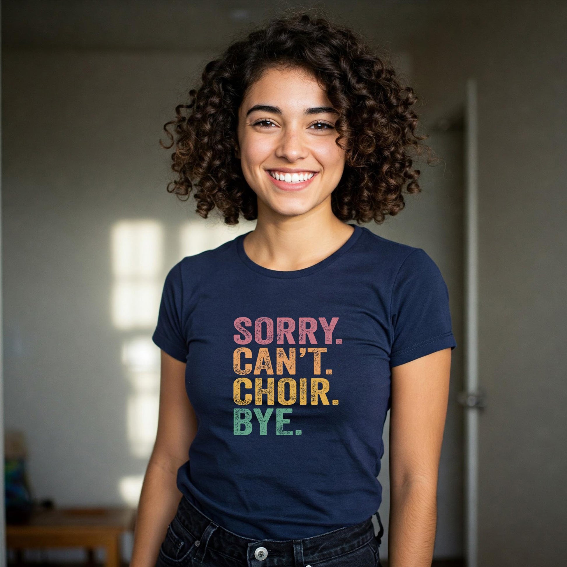 Person wearing a navy blue t-shirt with colorful text 'SORRY. CAN'T. CHOIR. BYE.'
