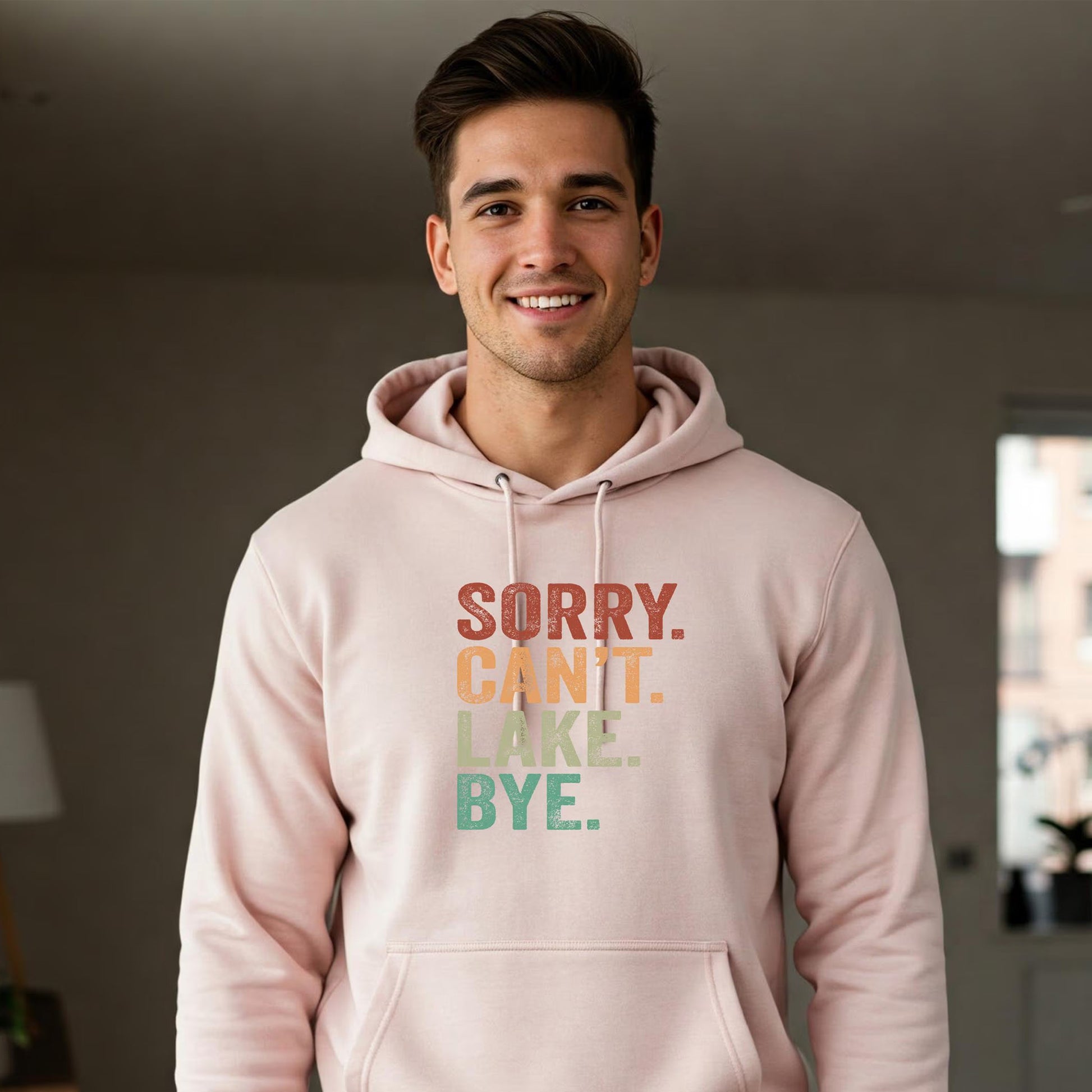 Man wearing a pink hoodie with text in a room.