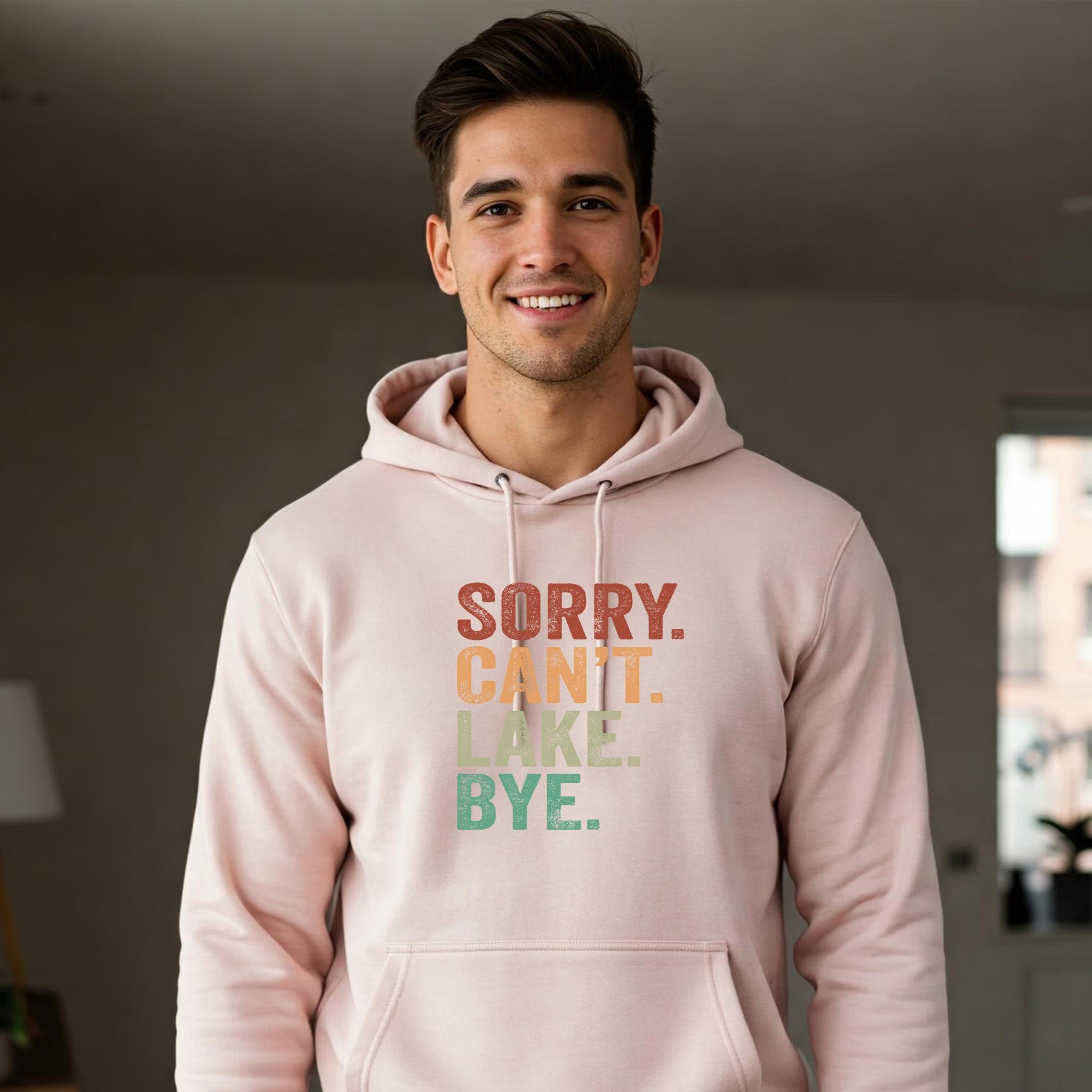 Man wearing a pink hoodie with text in a room.