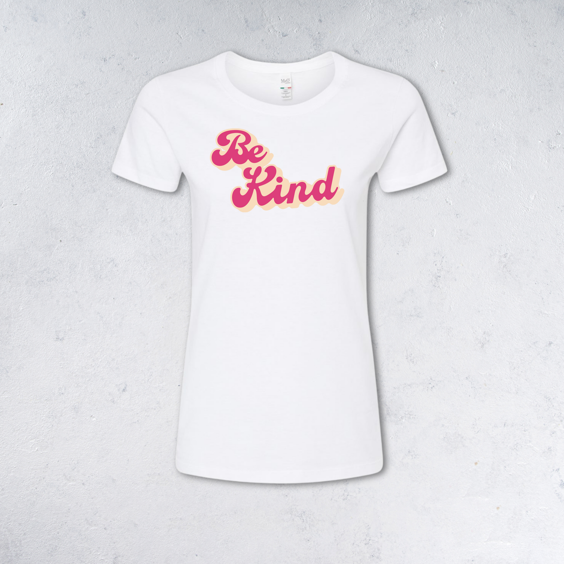 White t-shirt with 'Be Kind' text in pink and yellow on a light gray background
